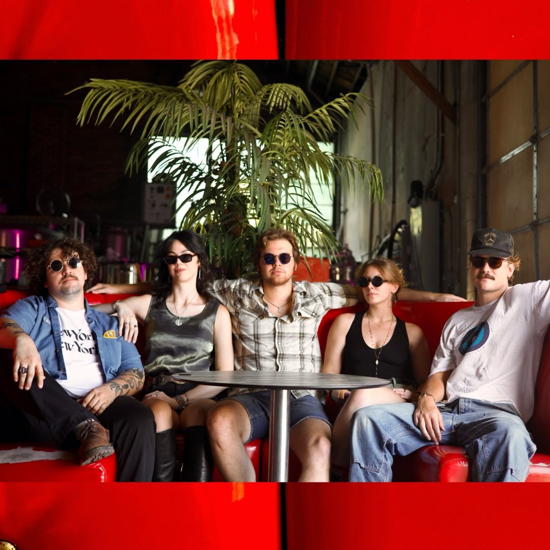 The five members of Oh? sitting together on a red booth in a warehouse bar